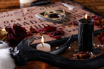 Wall Mural - Talking board and planchette, also known as Ouija board, used for communicating with the dead and other spirits. The atmosphere of black art with candles and horns of the animal.