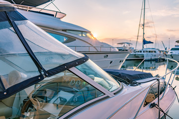 Cockpit and control panel of a small marine boat. Beautiful clear sunset in the sea harbor with moored yachts.