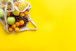 Textile eco bag with fruits on yellow background top-down copy space