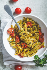 Poster - Green spinach pasta with tomatoes and herbs, top view. Healthy vegan food concept.