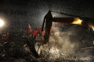 Rescue teams and excavator searching through the buildings destroyed during the earthquake.