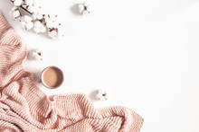 Cup of coffee, pink blanket, cotton flowers on white background. Flat lay, top view, copy space