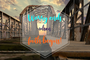 Biblical quote saying that worry ends when faith begins. On old abandoned railway metallic bridge with the sunset in the background