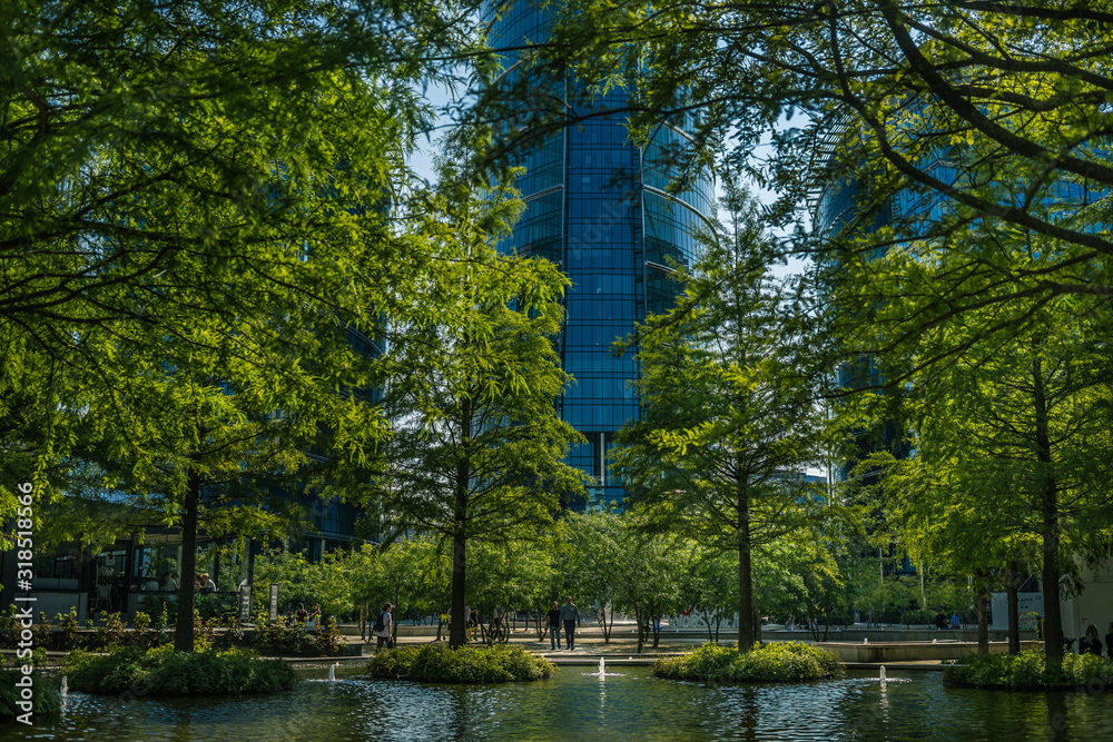 zielony park przy placu europejskim w Warszawie w tle szklany wierzowiec - obrazy, fototapety, plakaty 
