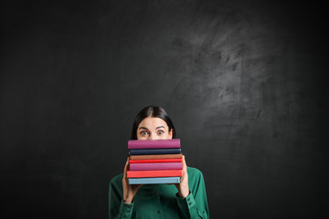 Wall Mural - Female teacher with books near blackboard in classroom