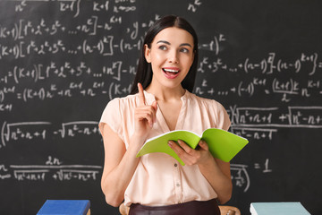 Wall Mural - Female teacher near blackboard in classroom