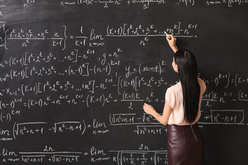 Wall Mural - Female teacher writing on blackboard in classroom