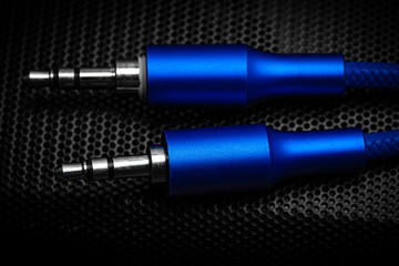 Poster - blue speaker cable jack against a dark background