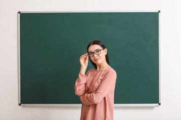 Wall Mural - Female teacher near blackboard in classroom