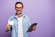 © deagreez - Portrait of confident corporate worker man hold blank space paper card badge occupation visit appointment bring online offer hold tablet wear denim jeans shirt isolated purple color background