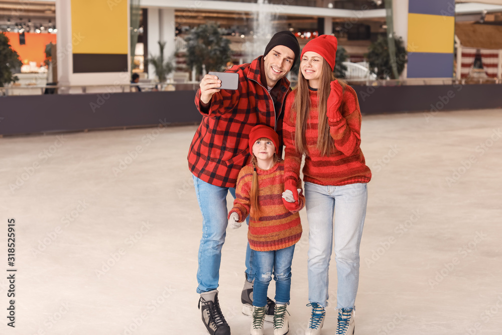 Happy family taking selfie on skating rink