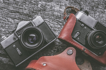 Two analog retro cameras lie on an old wooden table. Vintage tinted.