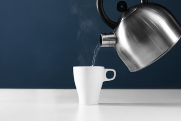 retro kettle pouring water into a cup on a white background with smoke on wood table