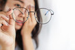 Asian woman hand holding eyeglasses having problem with eye pain, blur vision 