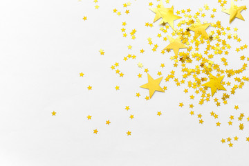 Gold confetti and stars and sparkles on a light background. Top view, flat lay. Copy text. Bright and festive background. For Christmas, New Year, Mother's Day.