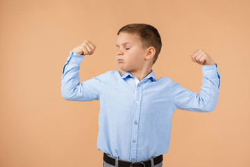 Wall Mural - little boy shows his biceps on beige background. child showing his muscles