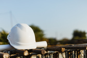 white helmet for security and blueprint on construction site