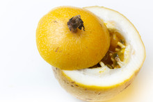 Passion Fruit On A White Surface With Top Cut Off And Partially Disclosing The Yellow And White Insides With Juicy Pulp And Black Seeds Visible