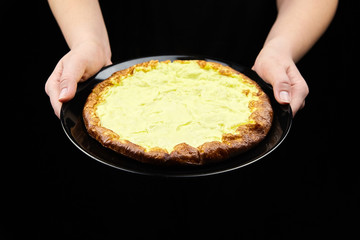 Cooked omelet in female hands on black background. Woman holds a plate with  omelette from chicken eggs