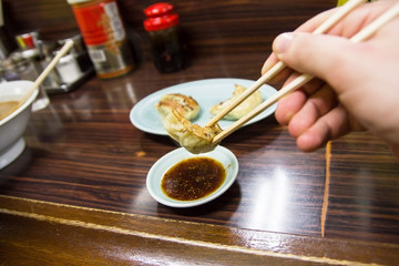 Wall Mural - The best way to eat Asian dumplings called Gyoza is to use chopsticks. Home restaurant in Japan food background.