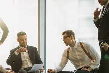 Wall Mural - coworking of young caucasian business people in office, wearing formal wear, leaders enjoy to be a part of successful business team. panoramic window in the background