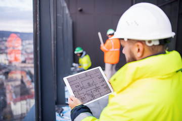Wall Mural - Man engineer standing on construction site, holding tablet.