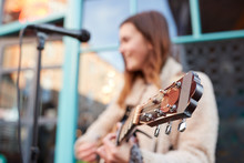 Focus On Guitar As Female Musician Busks And Sings Outdoors In Street