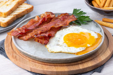 Breakfast - Fried Bacon Pieces And Eggs On A Plate.