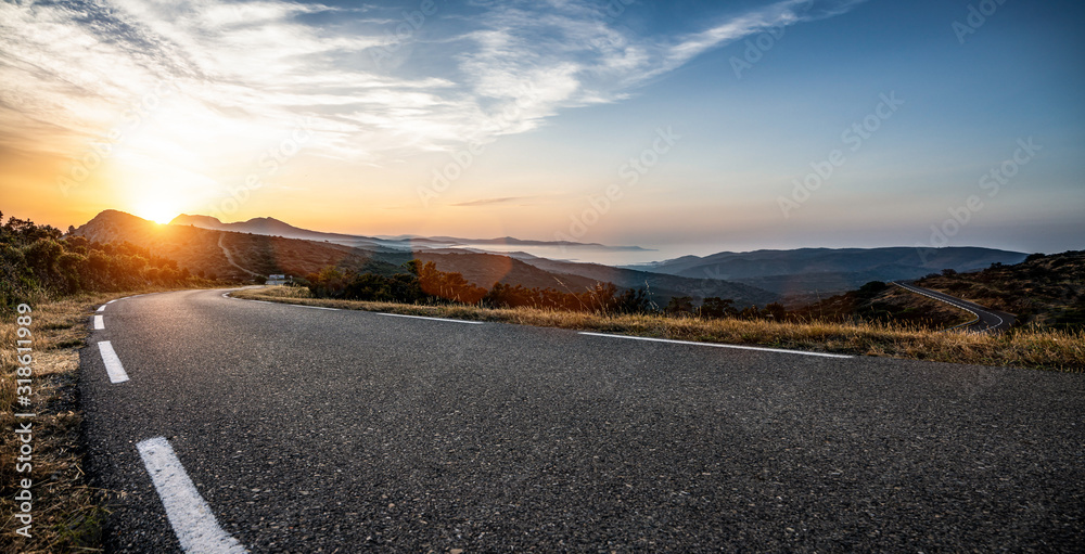 Empty long mountain road to the horizon on a sunny summer day at bright sunset - obrazy, fototapety, plakaty 