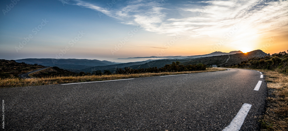 Empty long mountain road to the horizon on a sunny summer day at bright sunset - obrazy, fototapety, plakaty 