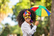 © Brastock Images - Young curly hair woman celebrating the Brazilian carnival party with Frevo umbrella on street.