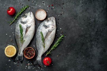 Fresh dorado fish with spices and ingredients tomato, razmorin, sunflower oil, lemon for cooking on a stone background with copy space for your text