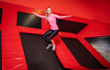 Fit young woman jumping on trampoline in fitness gym