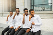 © Alexandr - four handsome young african men in white shirts with phones in their hands
