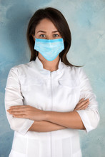 Doctor With Disposable Mask On Face Against Light Blue Background