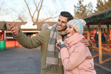 Poster - Happy couple in warm clothes at winter fair. Christmas season