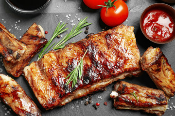 Delicious grilled ribs on black table, flat lay