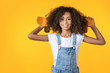 Happy preteen girl holding skateboard on her shoulder isolated on yellow background