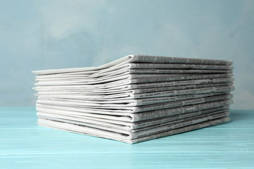 Stack of newspapers on light blue wooden table. Journalist's work