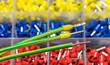 © KPixMining - Insulated cord pin end terminals on green electric conductors detail. Stripped copper wire or yellow crimped power cable connectors. Colored joining ferrules organized in plastic box. Selective focus.