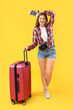 © Pixel-Shot - Female tourist with luggage on color background