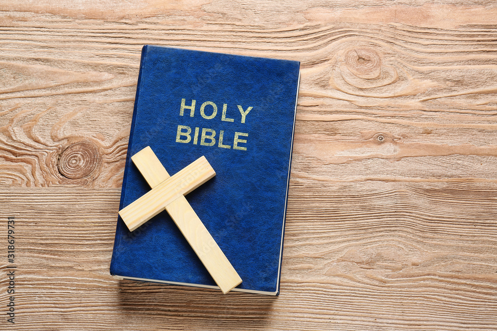 Christian cross and Bible on wooden background