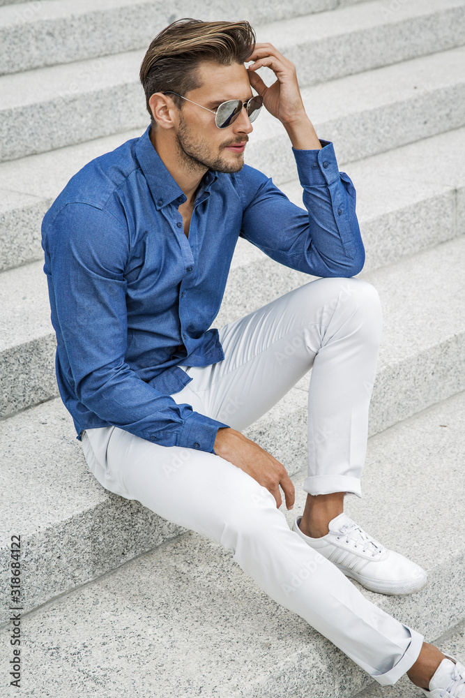 Fashionable handsome man wearing blue shirt and white pants Stock Photo | Adobe Stock Fashionable handsome man wearing blue shirt and white pants Stock Photo | Adobe Stock