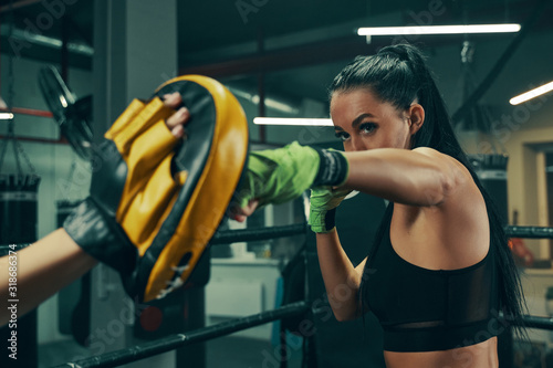 Fotografía Athletic woman during fight training on boxing ring wearing green bandages on ha