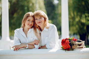 Elegant mother with young daughter. Family in a park. Women with a bouquet of flowers