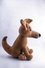 A brown amigurumi dog is shot by a photographer on a white background.