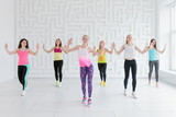 Young women in colorful sportswear at dance fitness class in white fitness studio