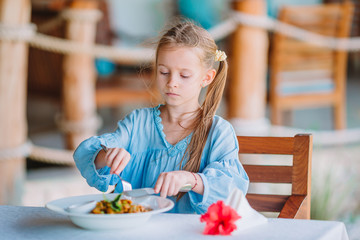 Adorable little girl having dinner at outdoor cafe