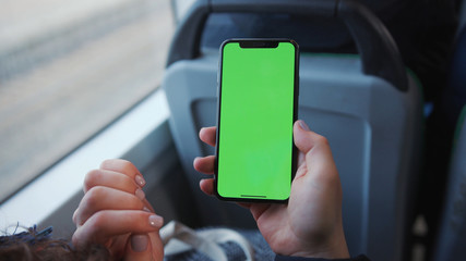 Lviv, Ukraine - May 19, 2018: Hands use touch holding a mobile telephone with a vertical green screen in tram chroma key smartphone technology cell phone street touch message display hand