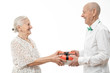 © Vasya - Cheerful elderly couple in white closes looking at each other and exchanging gifts isolated on white background, celebrating valentine's day
